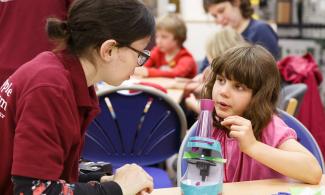 Child talking to Whipple Museum volunteer about microscopes