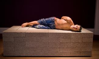 a sculpture of a man lying on breeze blocks