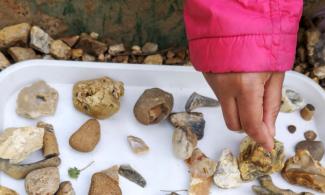 childs hand and gravel on a white tray