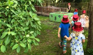 Children in red glittery top hats exploring the Botanic Garden