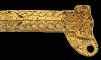 A gold dagger sheath with turquoise and lapis lazuli inlays