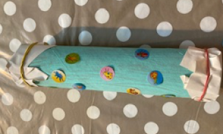Brightly coloured tube with ends sealed on grey background with white spots