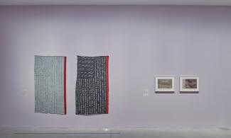installation view of the exhibition. Pink wall with a work of art hung on it.