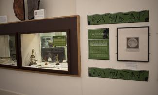 Museum exhibition; some scientific instruments behind a glass panel, a wall panel with a description of the objects