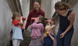 Family standing outside Museum looking through homemade telescopes