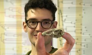 man with dark hair holding fossil bird skull