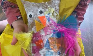 Child holding collage model of an owl