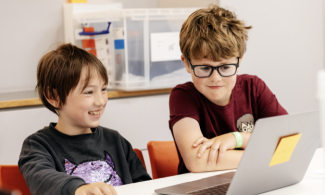 two boys looking at a computer screen