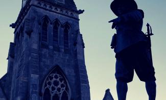 Silhouette of a church spire against a twilit sky