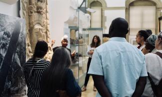 A group of people standing around a museum object