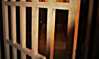 Image of a prison cell door in candlelight.