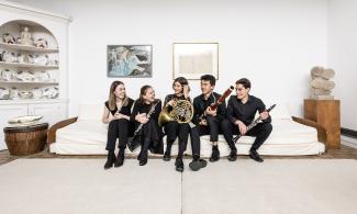 group of students holding instruments, sitting on a white sofa