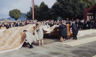 Tongan visitors and Māori hosts working together to lay the ngatu on the marae