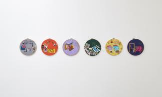 A white wall with six embroidery hoops hung upon it.