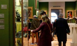 Some people gathered looking at a display of museum objects