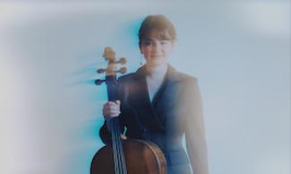 A woman in a suit holding a cello 