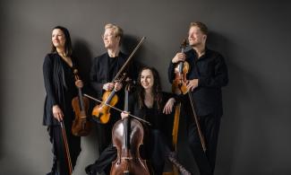 Four people in formal dress stood with instruments and looking off to the left