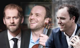 A group of men smiling and playing a violin