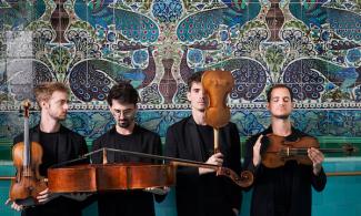 Four men in black suits holding string instruments