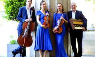 Two women in blue dresses, a man in a blue suit and a man in a black suit holding various instruments