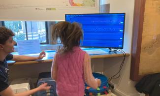 child jumping and looking at a screen showing the earthquake trace of her jump