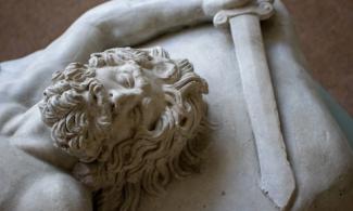 Statue of a bearded man, lying down and holding a sword