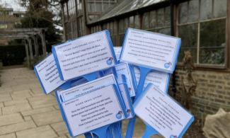 A series of poems written out on white paper and on sticks to be put in the ground.