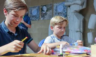 Two blonde children doing a craft activity in a museum gallery.