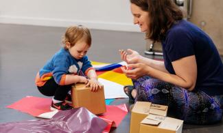 A child and adult exploring cardboard boxes 