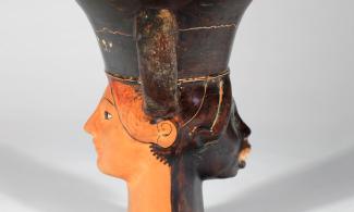 A ceramic vessel with two human faces on opposite sides, one Black and one white