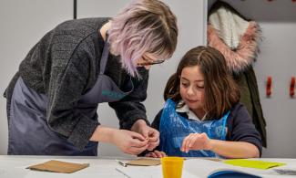 An adult and a child at a table doing a creative task