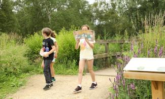 Children holding a map cross over a bridge in the Botanic Garden.