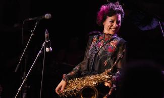 Hannah Horton holding her saxophone and smiling offstage.