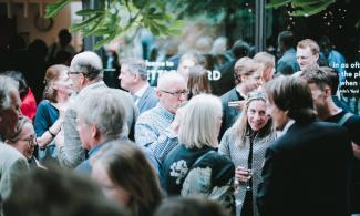 An outdoor courtyard with lots of people chatting and enjoying drinks