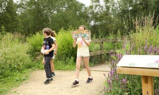 Children holding a map cross over a bridge in the Botanic Garden.