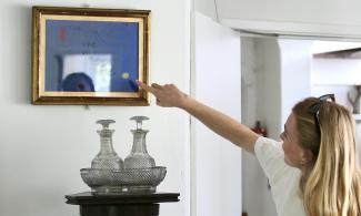 A woman with blonde hair pointing at an artwork in the Kettle's Yard house.