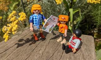 Playmobile characters holding a summer trail booklet