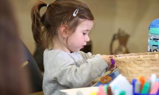 alt= "a young girl with brown hair plays with arts and crafts supplies"