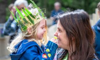 Young girl wearing a flower crown and smiling at her mum.