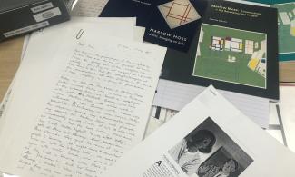Archival papers and books scattered across a desk.