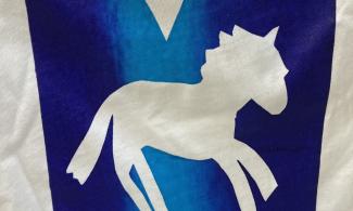 A white piece of fabric featuring a blue square. Inside the square is a white cut-out of a horse with a heart above it.