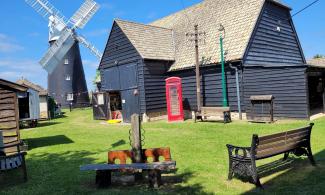 Burwell Museum exterior, a black barn with a mill in the background.