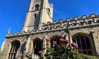 The exterior of Great St Mary’s church, with a blooming rose bush in the foreground.  