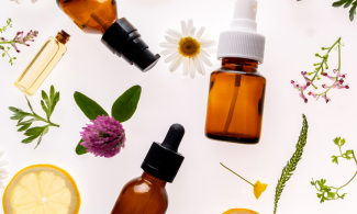 Brown glass bottles, plants, flowers and lemon slices on a pale background.