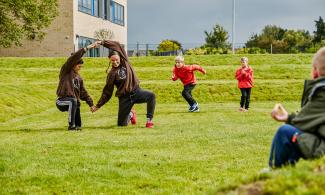 A group of people performing a dance routine on a large green playing field.
