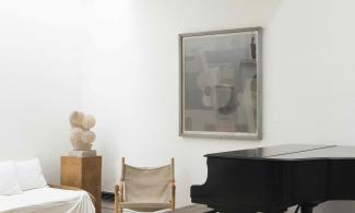 A corner in the Kettle's Yard house, with large white walls and a brick floor. There is a piano and stool.