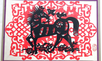 A paper cut artwork featuring a black horse and birds on a red background.