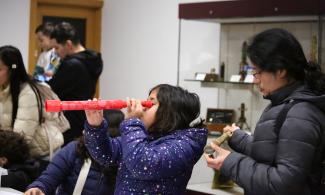 A young visitor in the Learning Gallery looking through a mini telescope from the handling box.