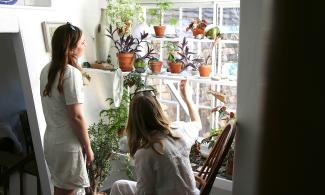 Two women looking at a window filled with plants in the Kettle's Yard house.