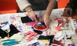 A woman pressing a stencil into a saucer of paint in a workshop at Kettle's Yard.